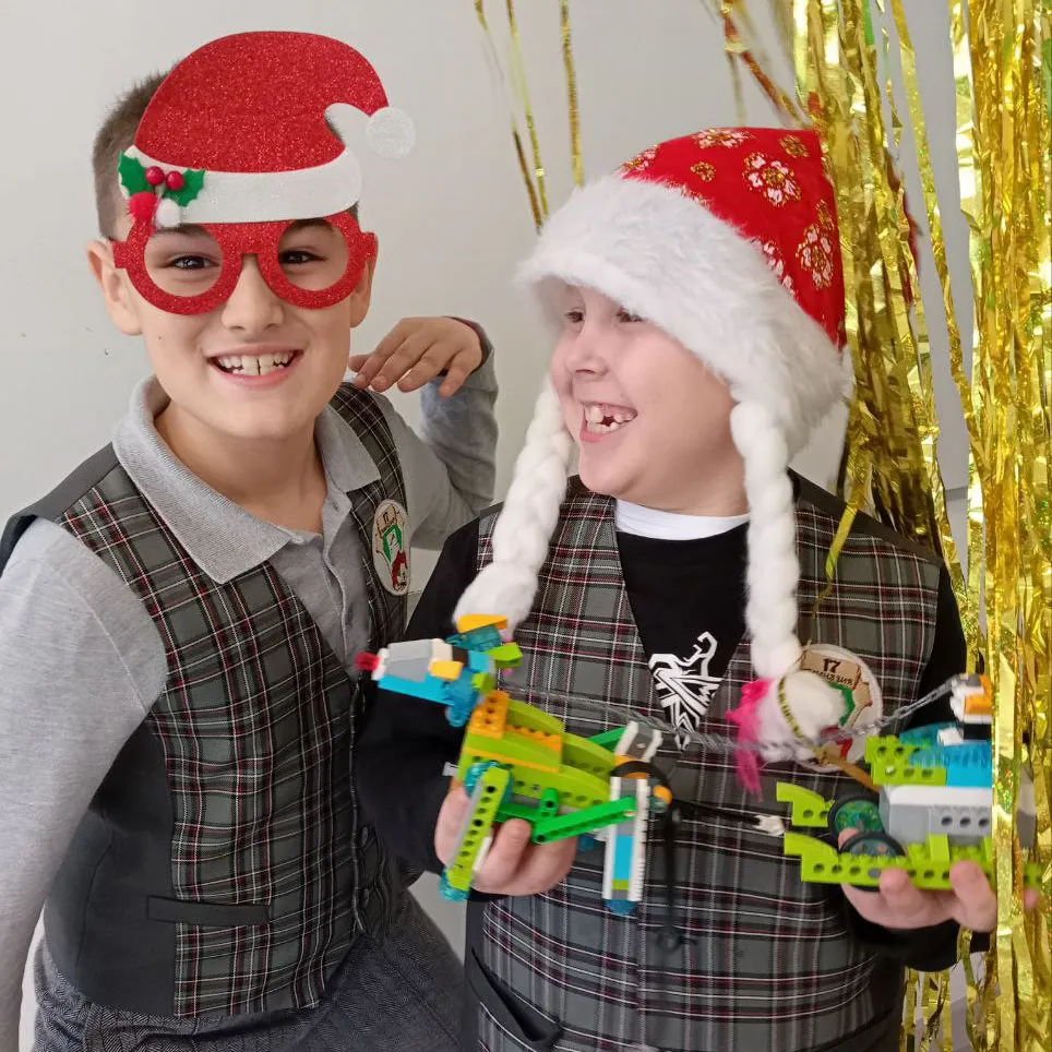 Двое мальчиков в новогодних шапках показывают собранные модели из LEGO на зимних РобоКаникулах в Лиге Роботов, Екатеринбург