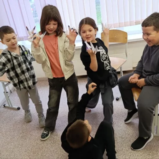 Дети на перемене в классе Лиги Роботов (Екатеринбург) играют и показывают бумажные «когти»-оригами, дружно смеются