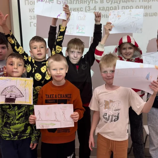Группа детей в классе Лиги Роботов (Екатеринбург) показывает рисунки проектов на фоне экрана
